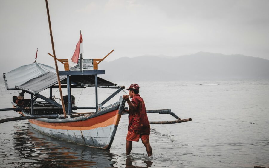 A fisher beside an outrigger boat at the shore