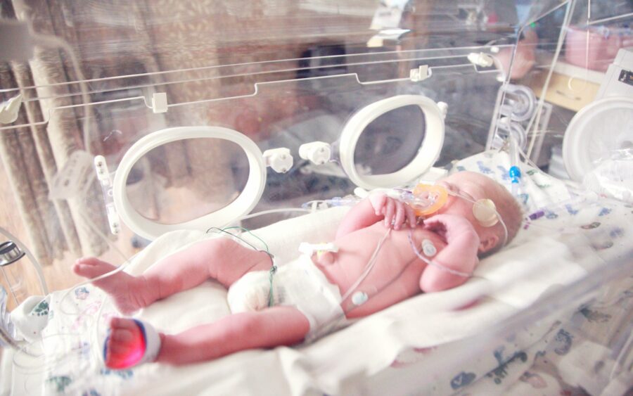 A newborn lying in a hospital incubator