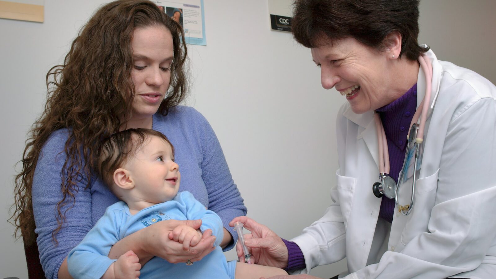 A doctor examines a young child on a parent's lap