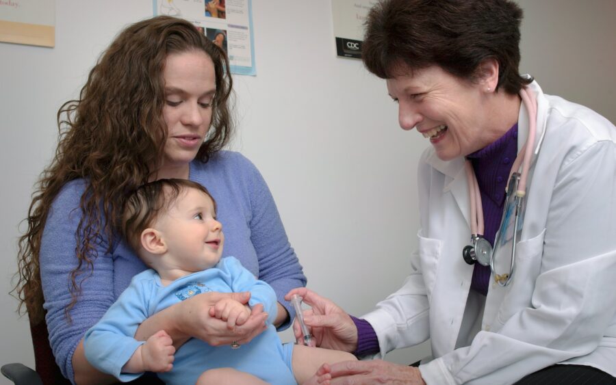 A doctor examines a young child on a parent's lap