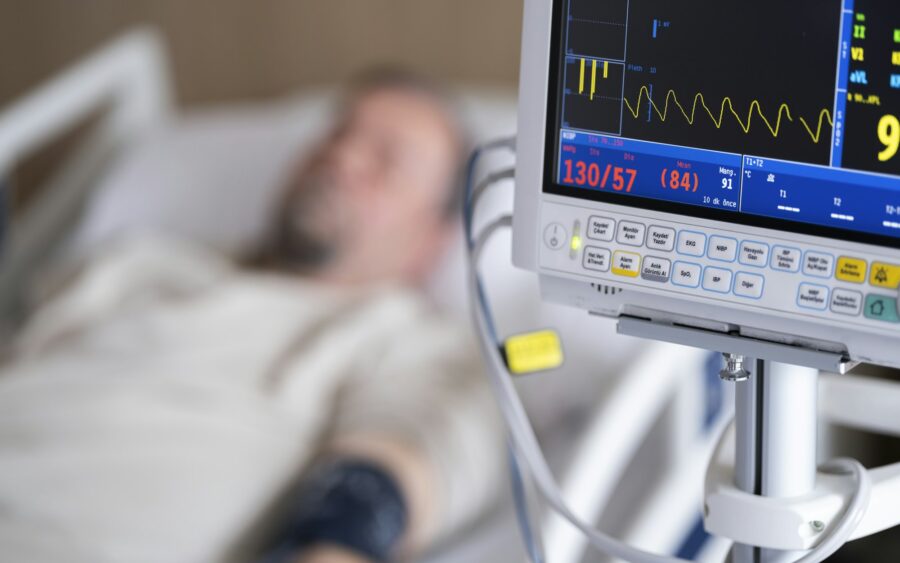 A patient in a hospital bed beside a monitor