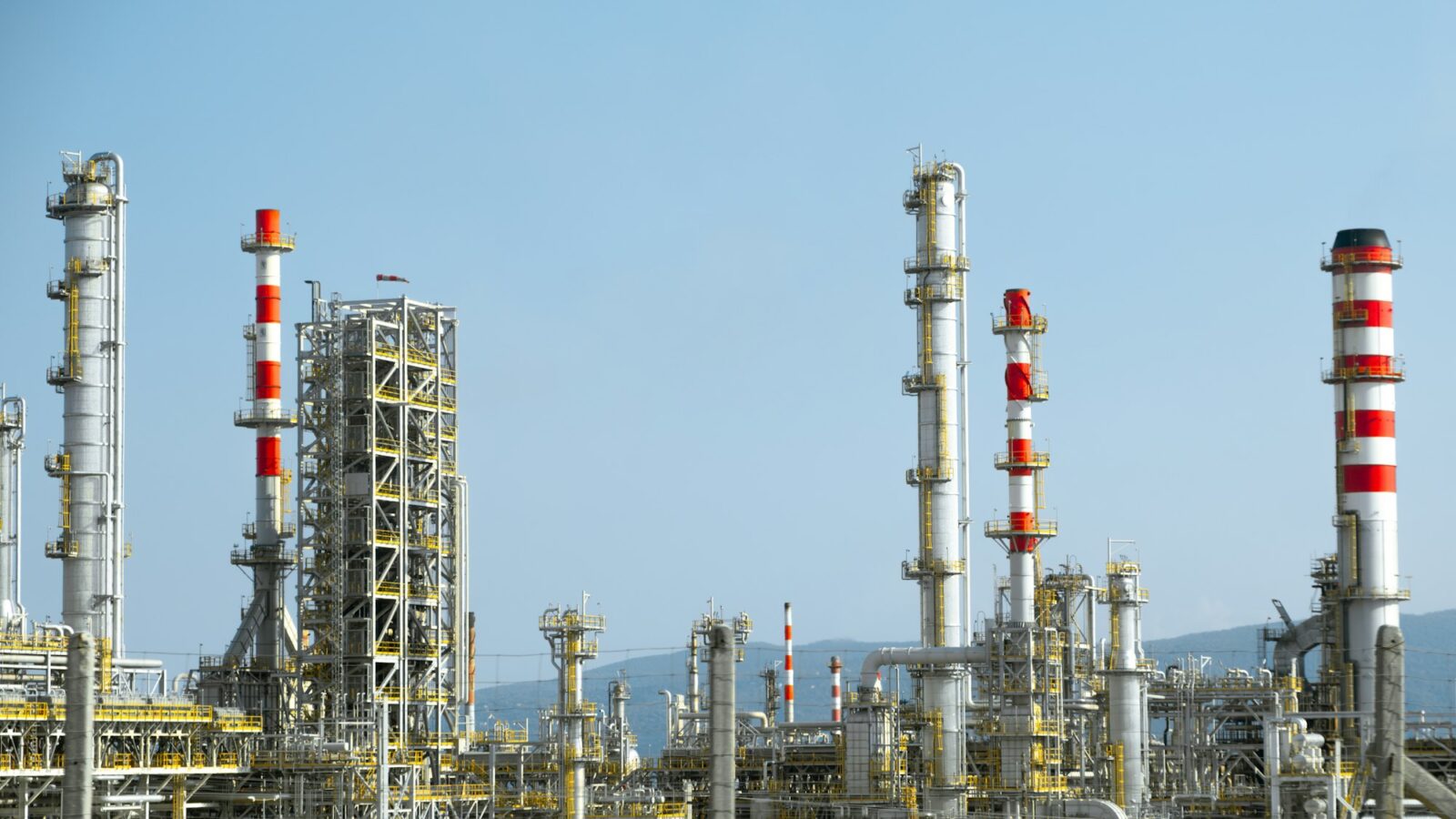An industrial plant with tall red and white stacks