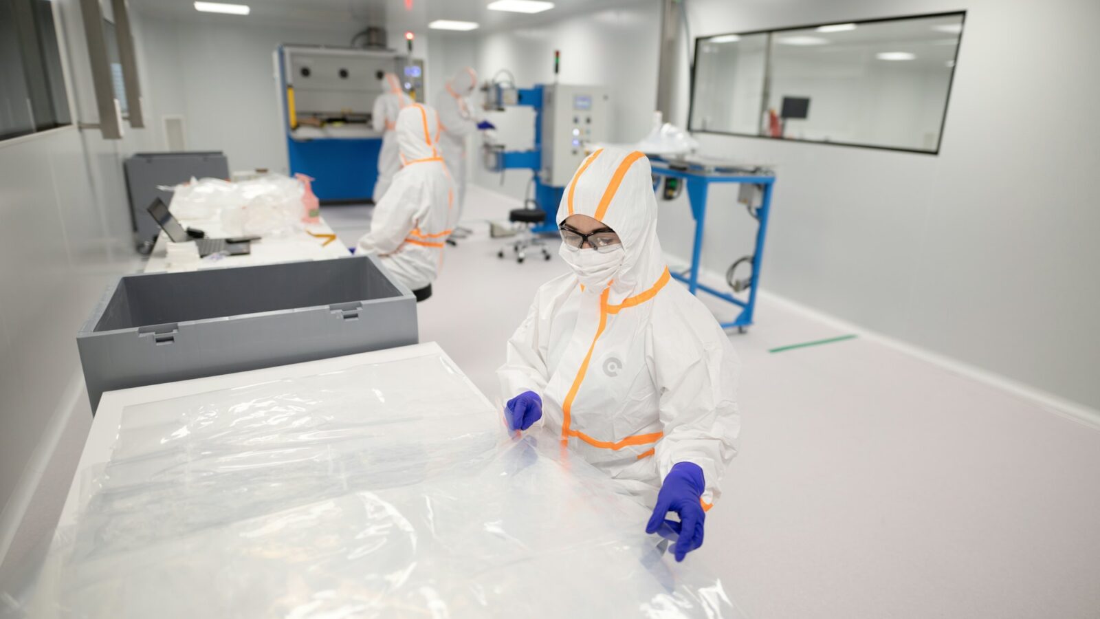 Workers in protective suits inside a cleanroom