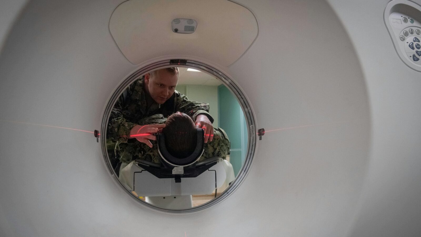 A technician positions a patient in a CT scanner