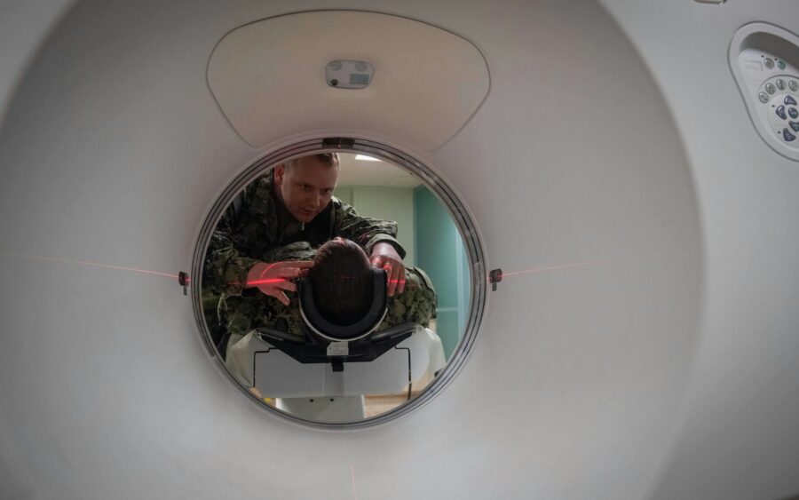 A technician positions a patient in a CT scanner