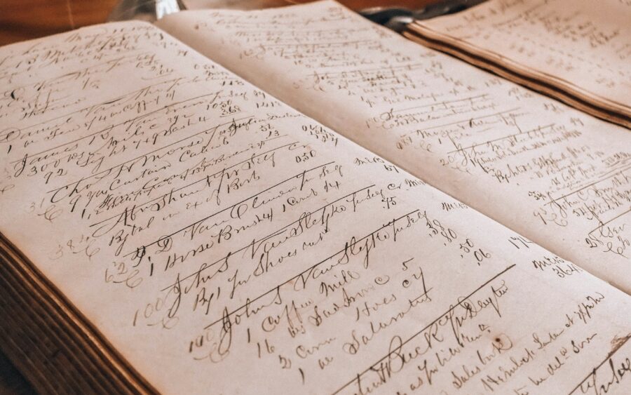 An old ledger with handwritten entries beside an inkwell